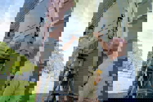 School maintenance staff working on a Bard exterior wall-mount air conditioner.