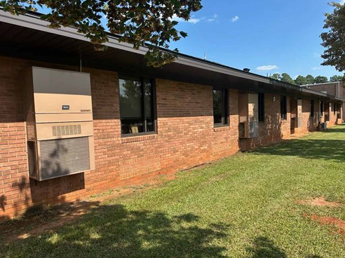 An elementary school wall with multiple Bard exterior wall-mount air conditioners used to cool individual rooms.